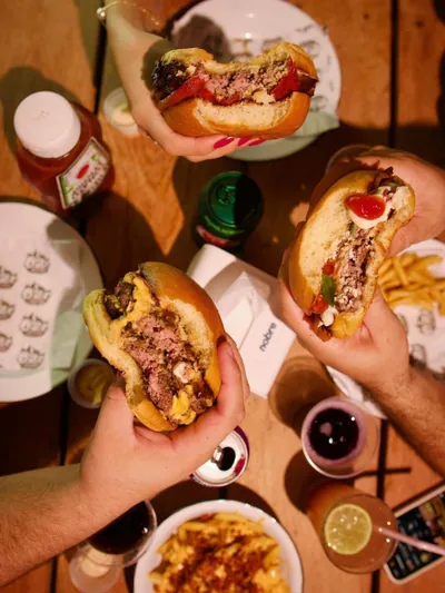 Amigos compartilhando burgers do Ô Zé